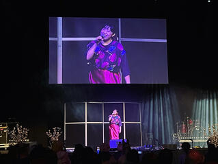 Caryl Loria Illana grinning on stage and on a big screen Caryl Loria Illana grinning on stage and on a big screen