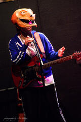 Caryl Loria Illana as Snarl in DinoRock: A Musical for Kids, rapping into a mic and wearing an electric guitar