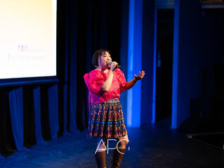 Caryl Loria Illana in a hot pink terno sleeved top and printed skirt, singing into a microphone