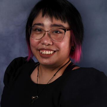 Caryl Loria Illana, a Filipina woman with light brown skin, freckles, brown eyes, and a black bob with hot pink at the front